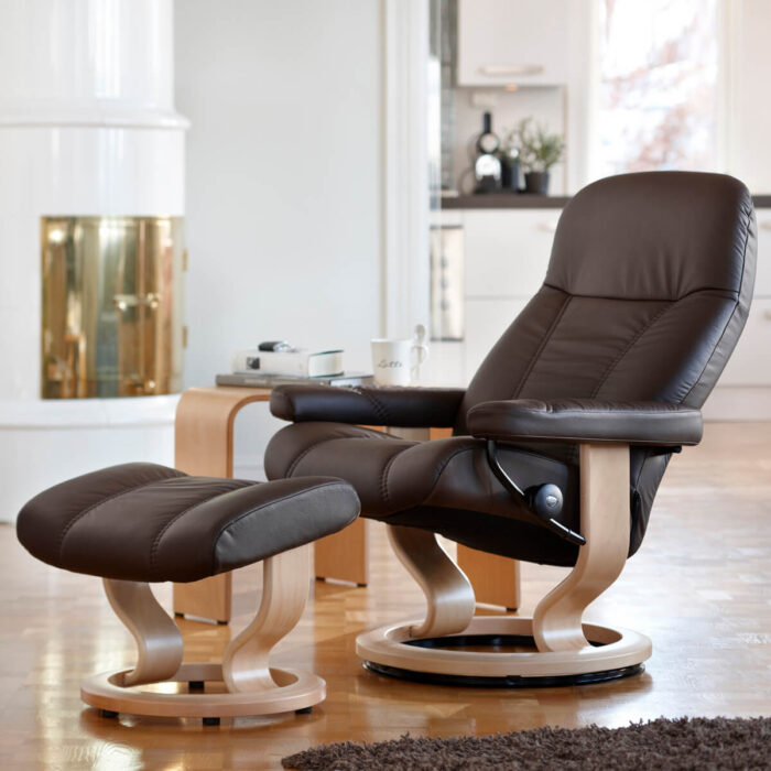 Fotografie von Stressless Sessel Consul im Wohnumfeld, Sessel und Hocker in Batick braun bezogen mit Classic Untergestell in Eichefarben gebeizt