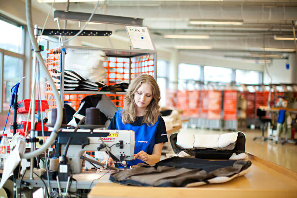 Bild aus der Stressless Fabrik in Norwegen. Eine Frau näht einen Lederbezug für einen Stressless Sessel